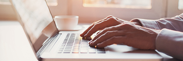 Gros plan sur des mains tapant sur le clavier d'un ordinateur portable.